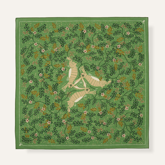 Green fabric with embroidered design of birds and leaves on a white background